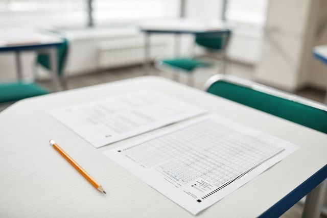Close-up of exam papers and a pencil on a classroom desk, ready for a test.